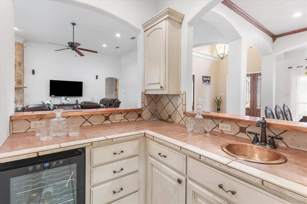 117 Redtail Court, Weatherford, TX 76088 Kitchen wet bar featuring painted cabinetry, tile countertops with decorative accents, an integrated wine refrigerator, and a recessed copper basin with a metal faucet