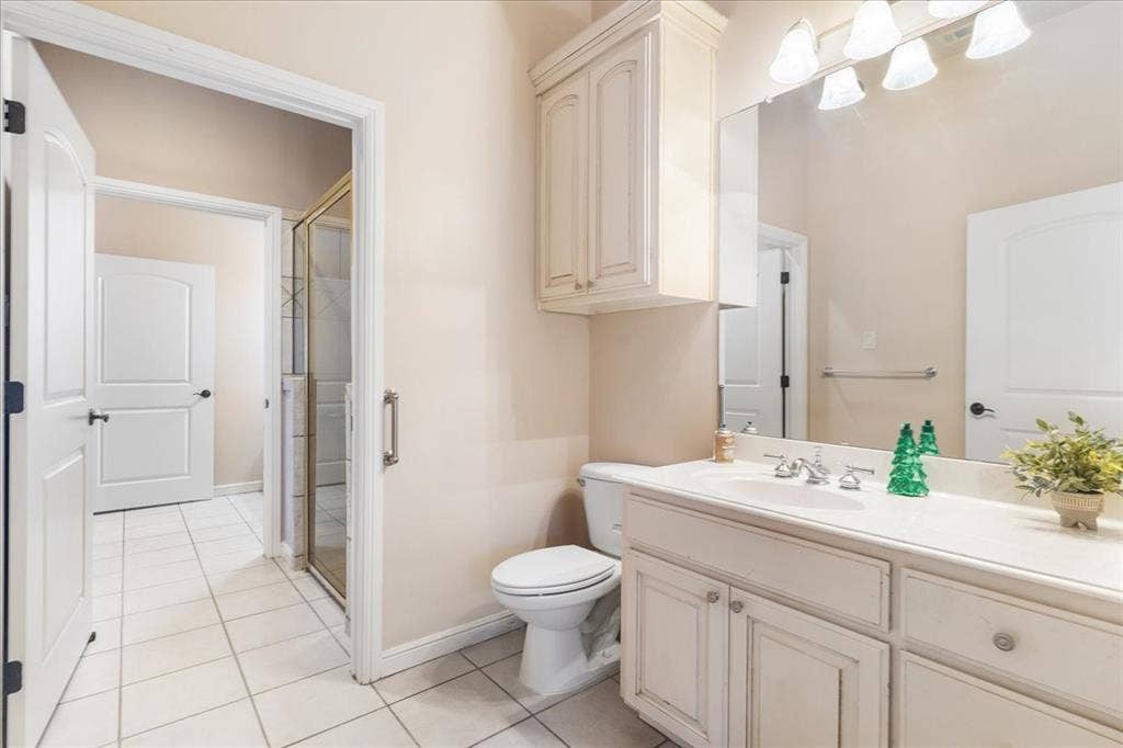 117 Redtail Court, Weatherford, TX 76088 Bathroom featuring a vanity with integrated cabinetry, an expansive wall-mounted mirror, overhead multi-bulb lighting, and tile flooring