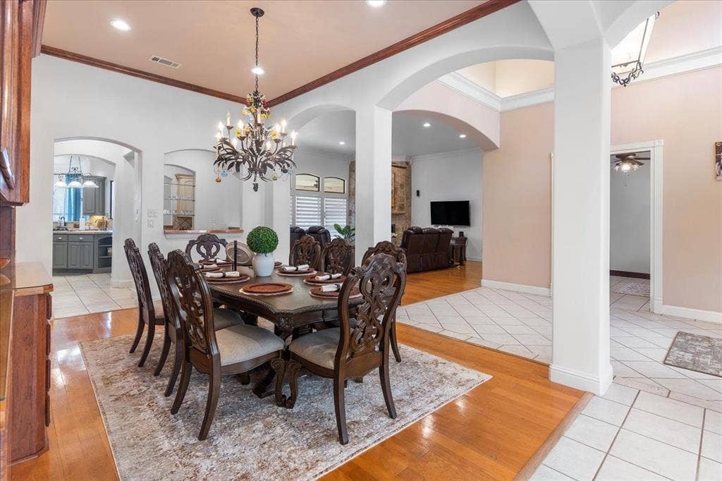 117 Redtail Court, Weatherford, TX 76088 Dining area featuring wood-finish flooring, decorative ceiling molding, arched architectural openings, and a multi-tiered metal chandelier
