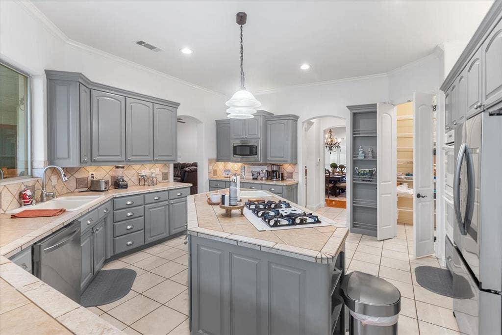 117 Redtail Court, Weatherford, TX 76088 Kitchen featuring grey shaker-style cabinetry, center island with a built-in cooktop, tiled countertops, stainless steel appliances, and tile flooring