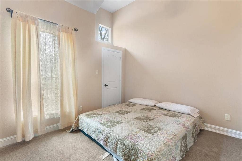 117 Redtail Court, Weatherford, TX 76088 Guest House. Bright secondary bedroom featuring neutral wall finishes, carpeted flooring, and abundant natural light from a sliding glass door with sheer curtains