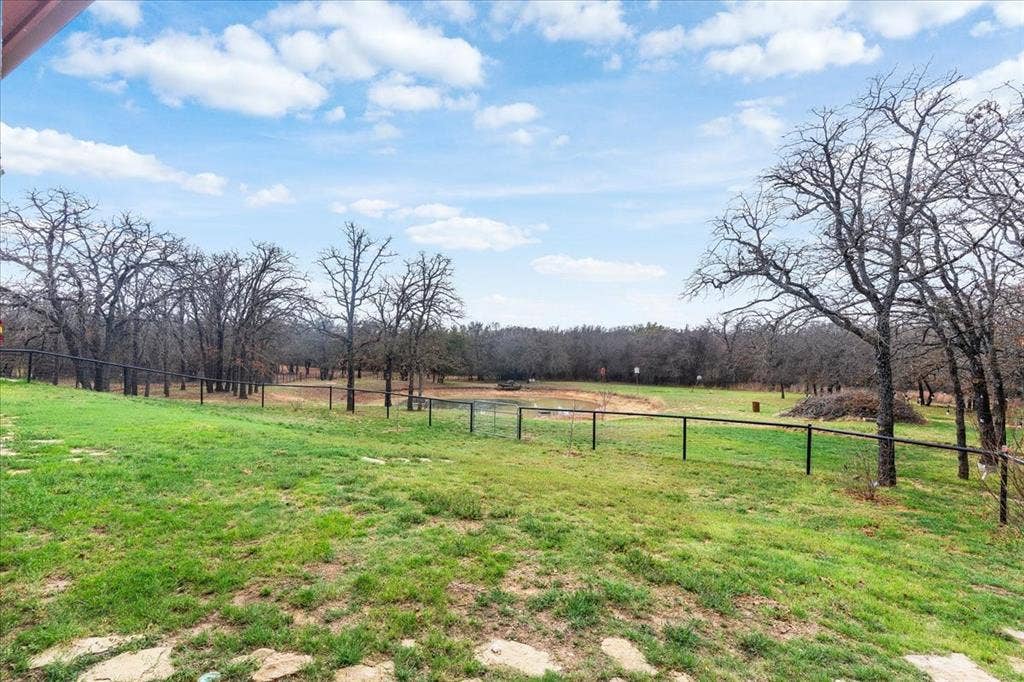 117 Redtail Court, Weatherford, TX 76088 Expansive green space featuring mature trees, a perimeter fence, and a natural pond