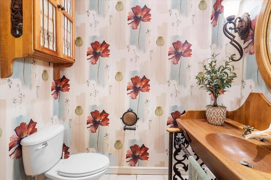 117 Redtail Court, Weatherford, TX 76088 Powder room showcasing decorative wallpaper with floral and geometric patterning, white ceramic fixtures, wood-finish vanity with integrated sink, ornate mirror with wood frame, and decorative ceramic vessel accents