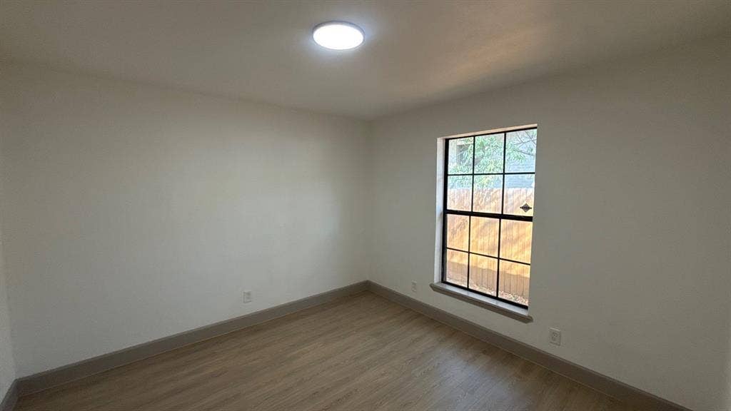 7437 Eccles Drive, Dallas, TX 75227 Interior space featuring neutral wall paint, wood-finish flooring, a grid-pattern window, and a flush-mount ceiling light fixture