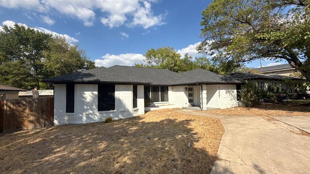 7437 Eccles Drive, Dallas, TX 75227 Single-story exterior featuring a white masonry façade, dark-toned hip roof, concrete driveway, and a front entry door with glass paneling