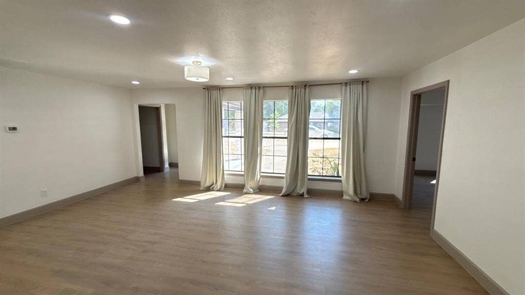 7437 Eccles Drive, Dallas, TX 75227 Living area featuring wood-finish flooring, recessed lighting, and a central semi-flush mount light fixture, highlighted by a bank of three large multi-pane windows