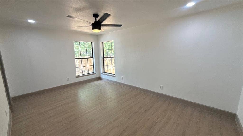 7437 Eccles Drive, Dallas, TX 75227 Neutral-toned room featuring wood-finish flooring, recessed lighting, a ceiling fan, and multi-pane windows with dark frames