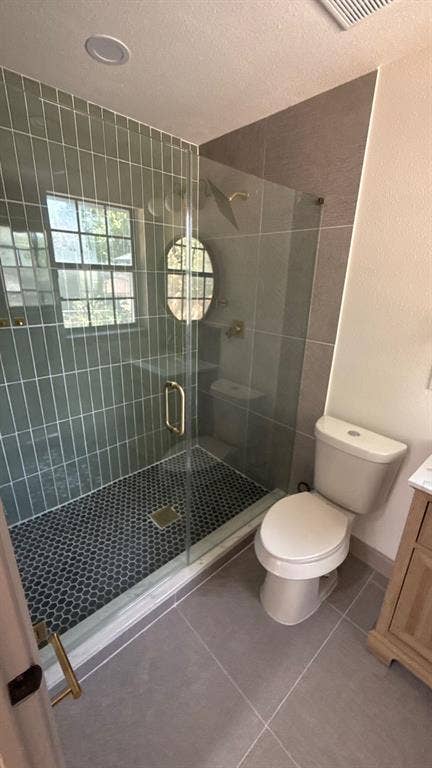 7437 Eccles Drive, Dallas, TX 75227 Walk-in shower featuring vertical tile walls, glass enclosure, and penny-round tile flooring