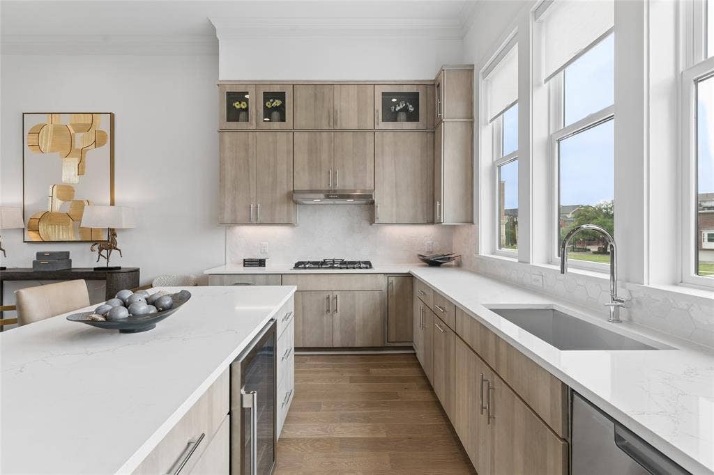 2401 Canton Street, #1002, Dallas, TX 75201 The kitchen is flooded with natural light and offers stacked upper cabinetry, Fisher & Paykel appliances, quartz surfaces and a designer tile backsplash. Image of model home with similar layout.