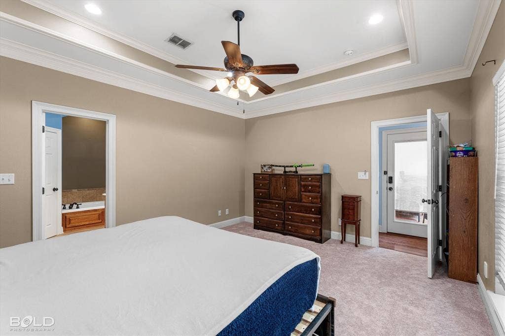 Tray ceiling with crown molding, recessed lighting, and a central ceiling fan
