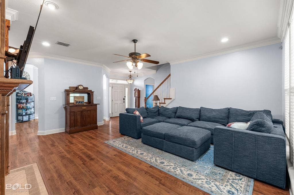 Living area featuring wood-finish flooring, crown molding, recessed lighting, and a ceiling fan with integrated light fixture