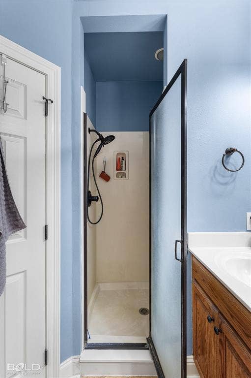 Walk-in shower featuring a glass door with dark trim, wall-mounted adjustable showerhead, and a built-in recessed soap niche