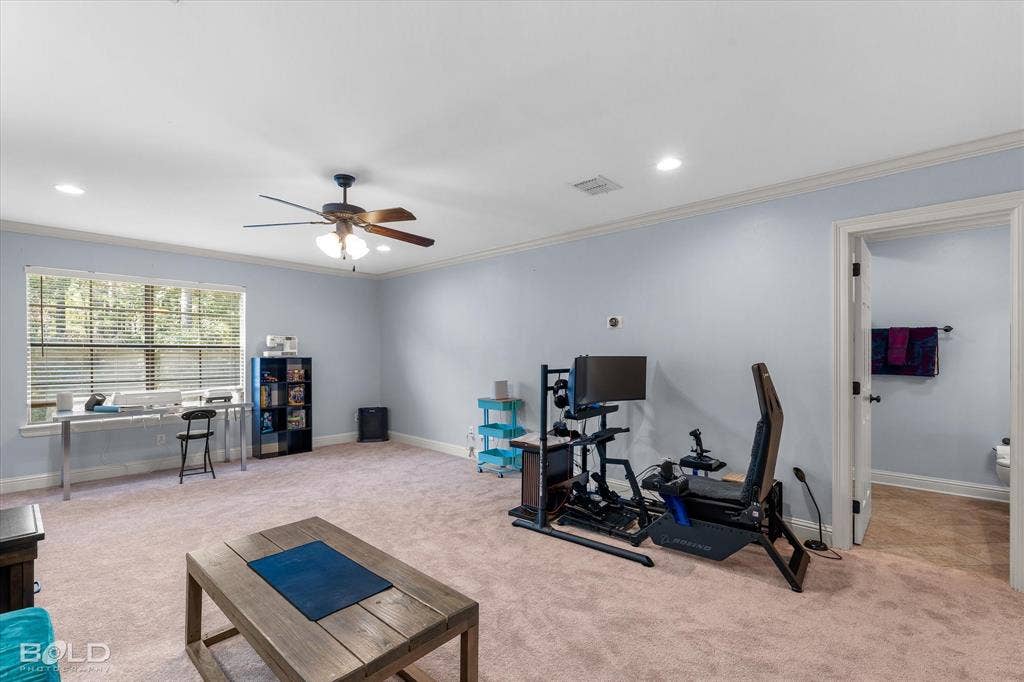 Spacious room featuring neutral carpeting, crown molding, recessed lighting, and a ceiling fan with integrated lighting
