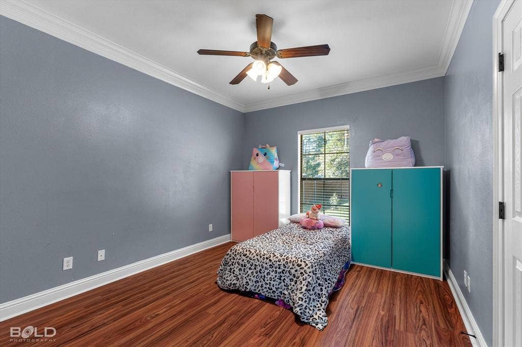Room featuring wood-finish flooring, crown molding, and a ceiling fan with integrated lighting
