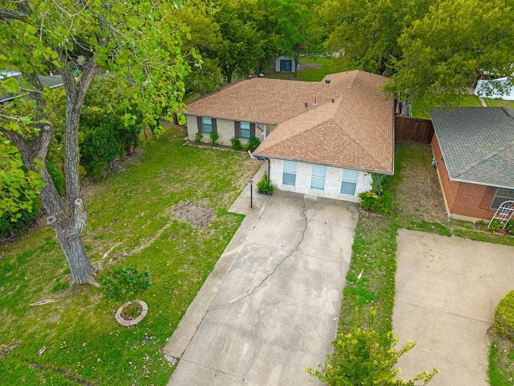 203 Evelyn Street, DeSoto, TX 75115 Single-story residence featuring a light-toned brick facade, asphalt shingle roof, attached concrete driveway, and mature landscaping
