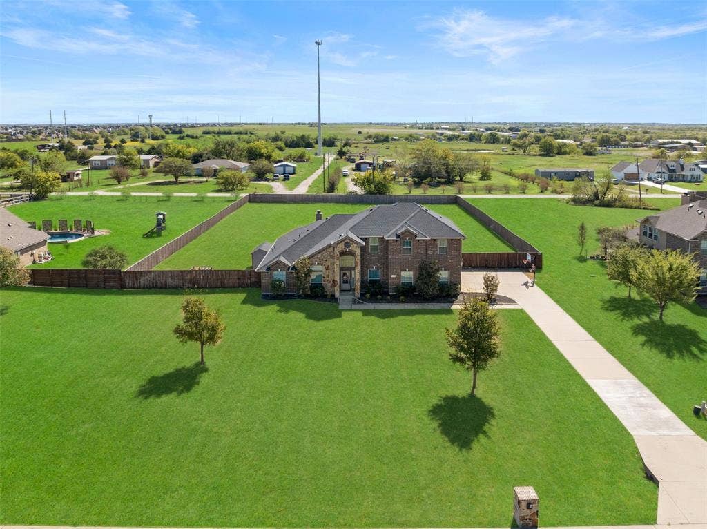 13176 Franklin Lane, Talty, TX 75126 Multi-level brick exterior featuring a multi-gabled roofline, an expansive lawn, a concrete driveway, and a fenced backyard