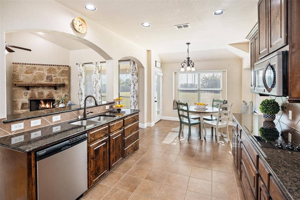 13176 Franklin Lane, Talty, TX 75126 Kitchen featuring dark-finish cabinetry, stone countertops, recessed lighting, tile flooring, and a stone-accented fireplace