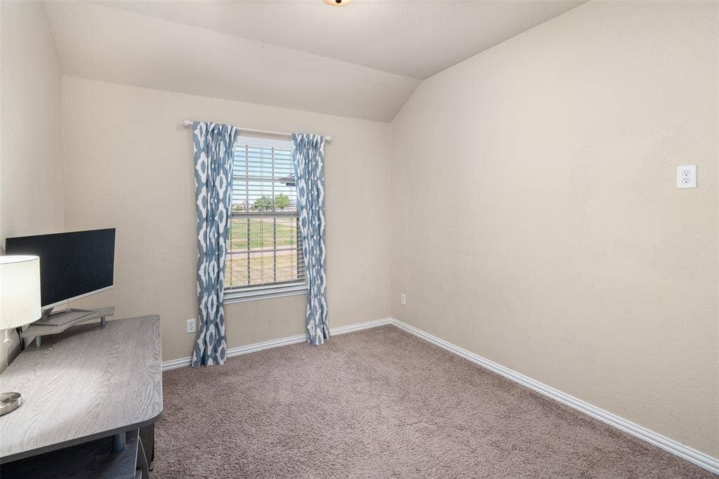 13176 Franklin Lane, Talty, TX 75126 Room featuring neutral-toned carpeting, vaulted ceilings, and a window with blinds