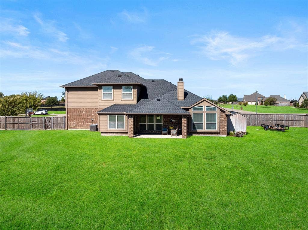 13176 Franklin Lane, Talty, TX 75126 Two-story residence featuring a brick and siding exterior, asphalt shingle roof, rear covered patio, and fenced-in backyard