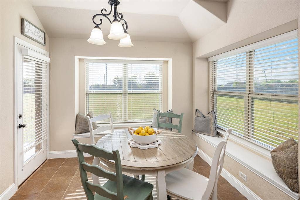 13176 Franklin Lane, Talty, TX 75126 Sun-drenched breakfast area featuring built-in window seating, tile flooring, tray ceiling, and a multi-arm chandelier