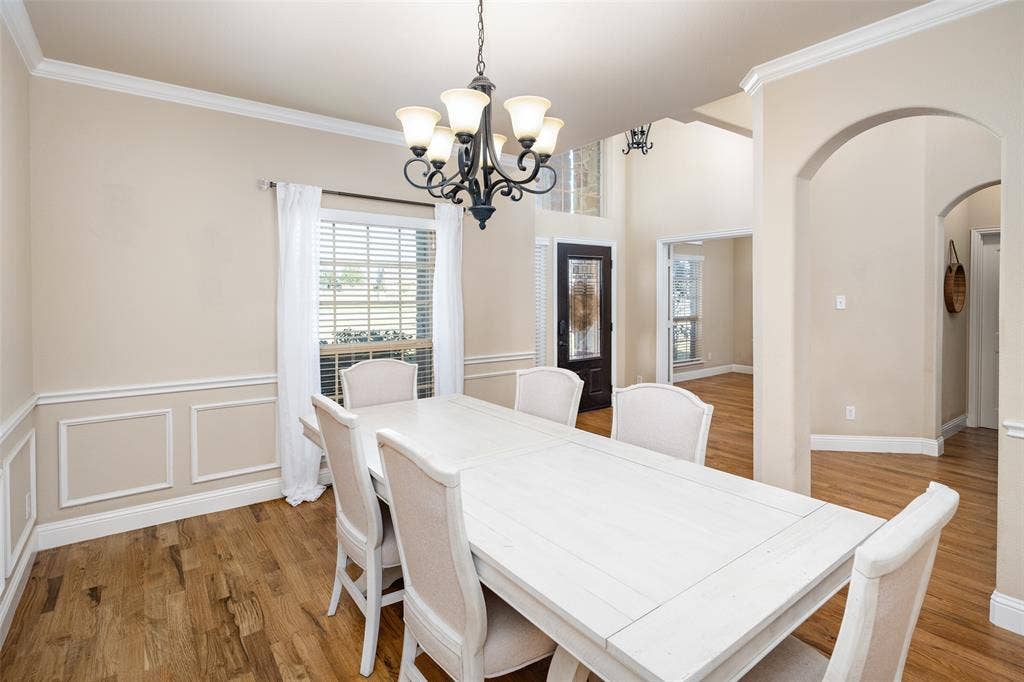 13176 Franklin Lane, Talty, TX 75126 Dining area featuring wood-finish flooring, wainscoting, an arched doorway, and a multi-light chandelier