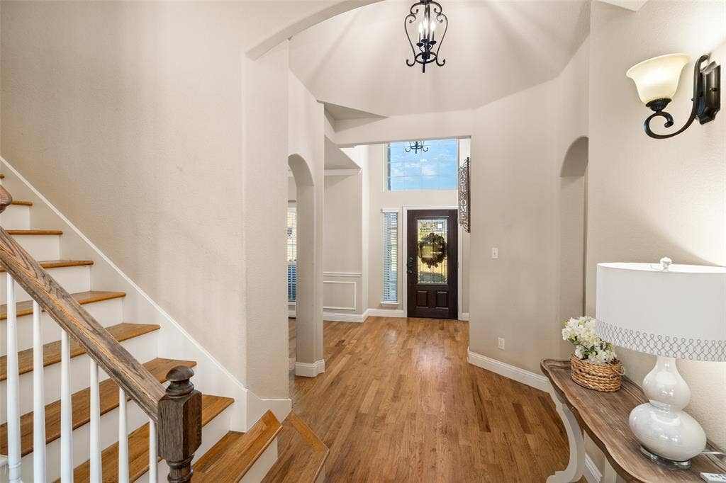 13176 Franklin Lane, Talty, TX 75126 Foyer featuring high ceilings, wood-finish flooring, staircase with wood handrails, arched architectural details, and a multi-pane glass entry door