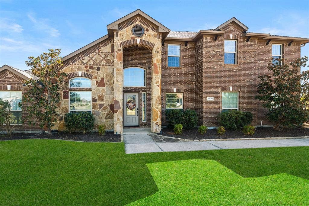 13176 Franklin Lane, Talty, TX 75126 Two-story exterior featuring multi-tonal brick and stone veneer, arched windows, a recessed front entry with a decorative arched transom, and an expansive lawn