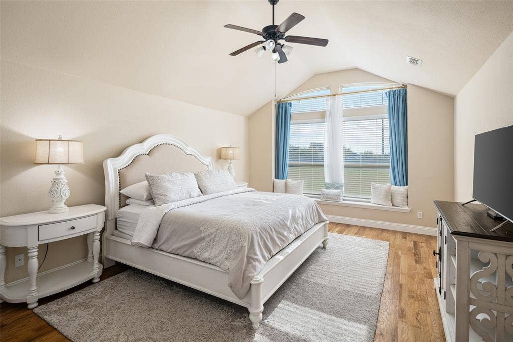 13176 Franklin Lane, Talty, TX 75126 Vaulted ceiling featuring a central blade-style fan, expansive windows with a deep built-in ledge, and wood-finish flooring