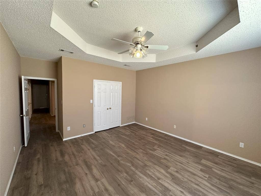 7800 Crestview Drive, Plano, TX 75024 Tray ceiling featuring a built-in ceiling fan, wood-finish flooring, and a double-door closet