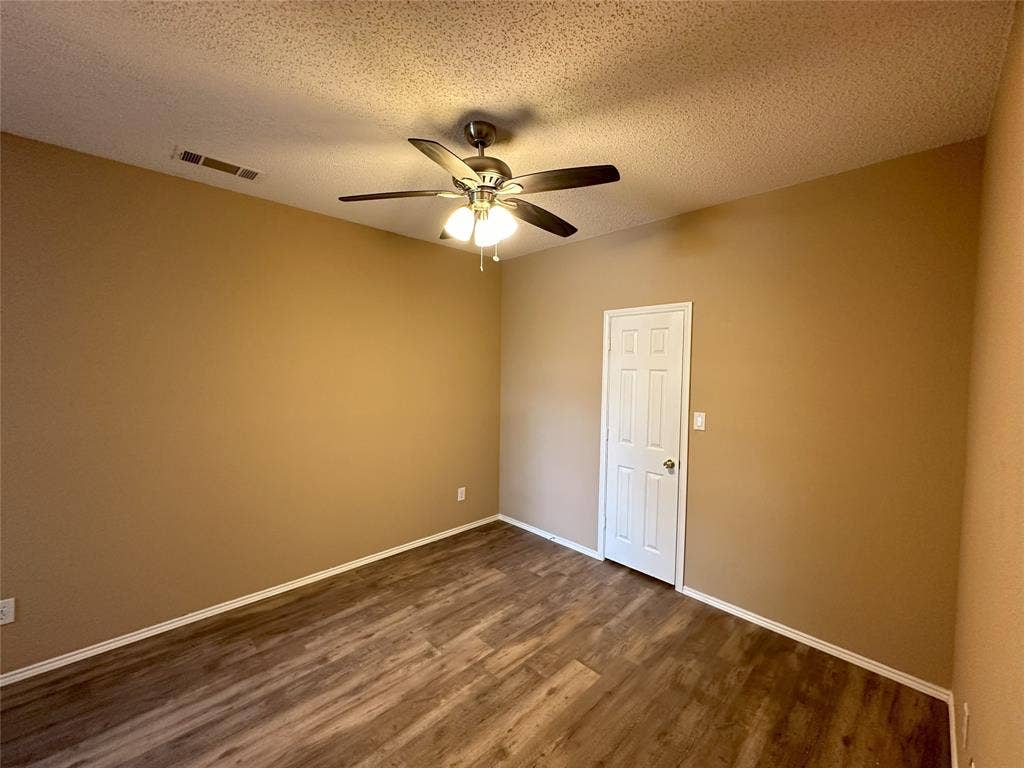7800 Crestview Drive, Plano, TX 75024 Wood-finish flooring with neutral wall tones and a white paneled door