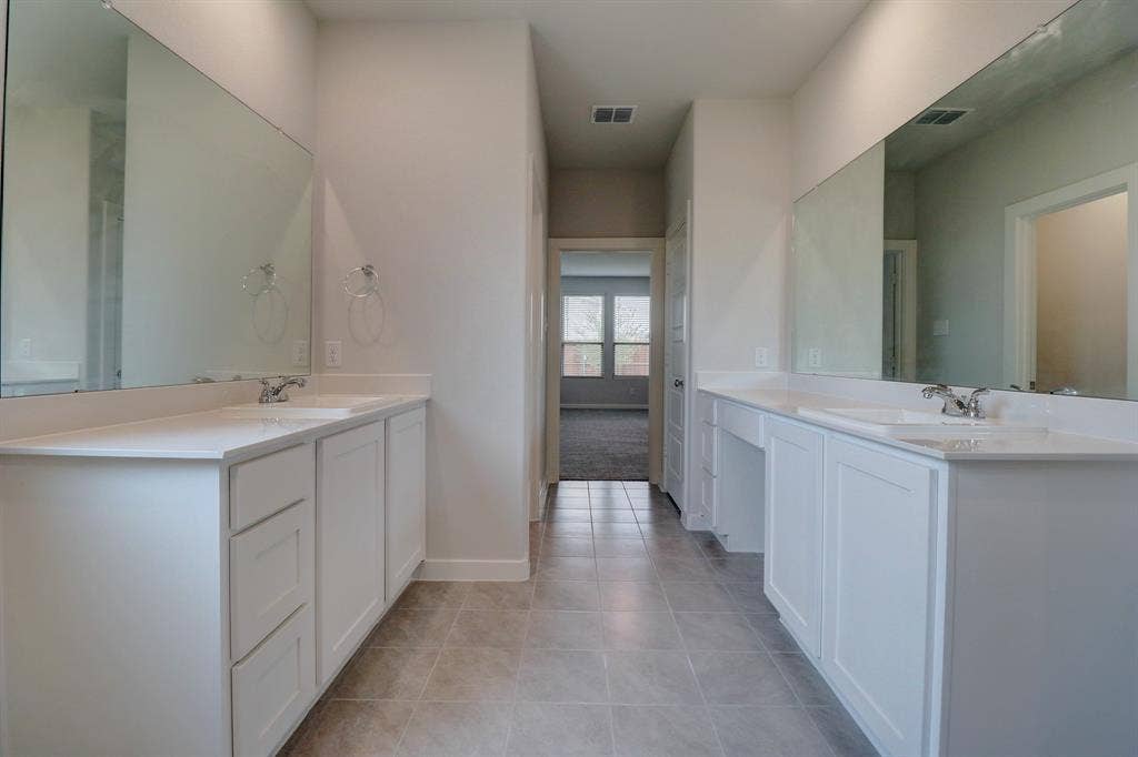 Dual vanity with integrated sinks, white cabinetry, expansive mirrors, tiled flooring, and recessed lighting