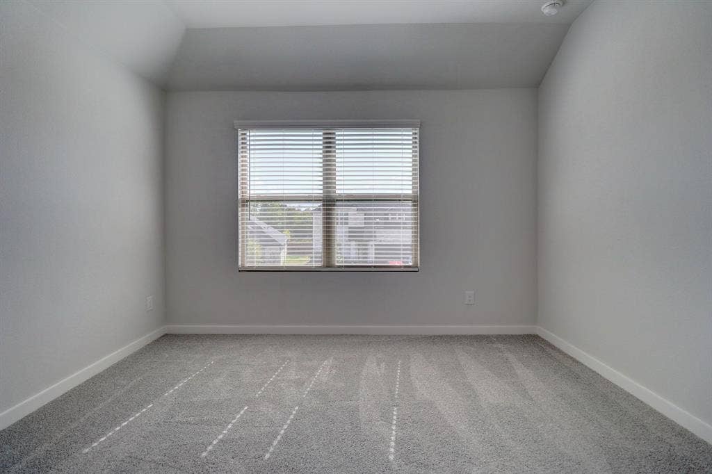 Recessed ceiling with an integrated light fixture, window with horizontal blinds, and gray patterned carpet