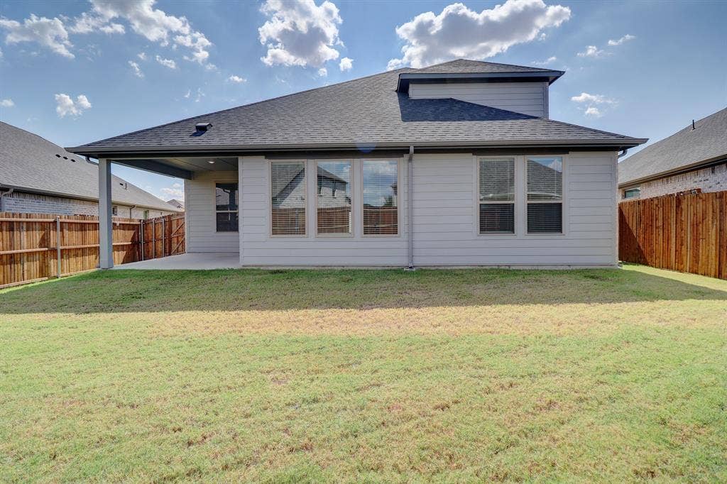 Exterior featuring a covered patio, multiple windows, and a fenced yard