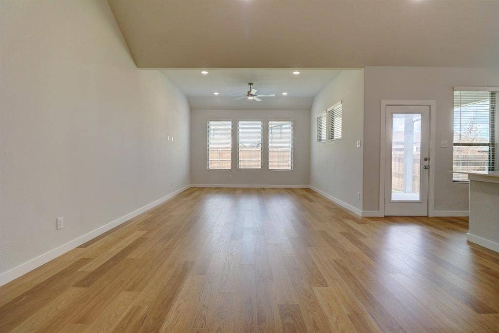 Wood-finish flooring throughout, vaulted ceiling, recessed lighting, ceiling fan, and multiple windows with blinds