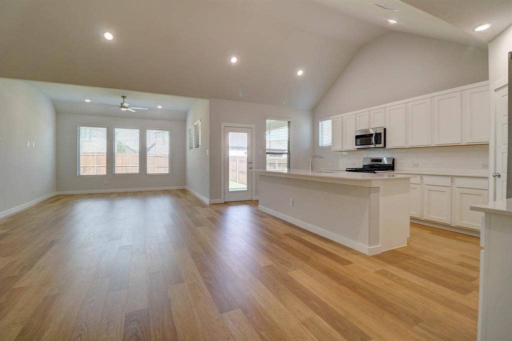 Open-concept layout featuring wood-finish flooring, a vaulted ceiling, and recessed lighting