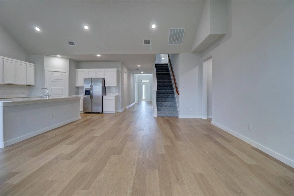 Spacious open-concept layout with wood-finish flooring, recessed lighting, and a kitchen island with sink