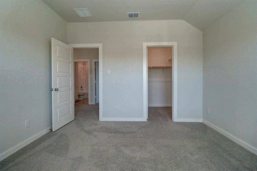 Wall-to-wall carpeting with light gray walls, an open closet with built-in shelving, and a five-panel interior door