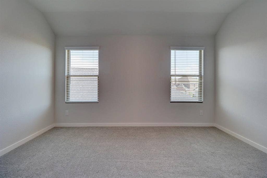 Vaulted ceiling with textured walls, two windows, horizontal blinds, and gray carpeting