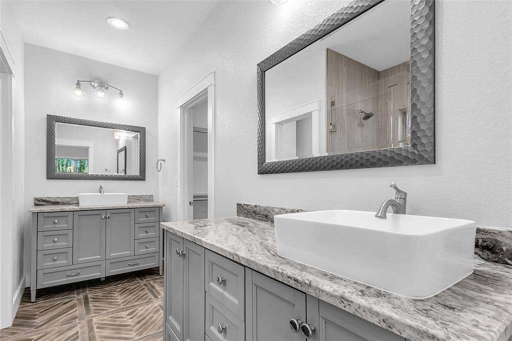 239 Colonial Drive, Mabank, TX 75156 Oversized walk-in glassed shower has a stained concrete floor, corner shelves and a custom tile wall design. Door in photo opens to the private water closet