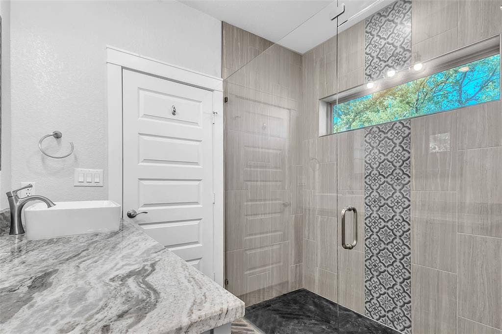 239 Colonial Drive, Mabank, TX 75156 Oversized walk-in glassed shower has a stained concrete floor, corner shelves and a custom tile wall design. Door in photo opens to the private water closet