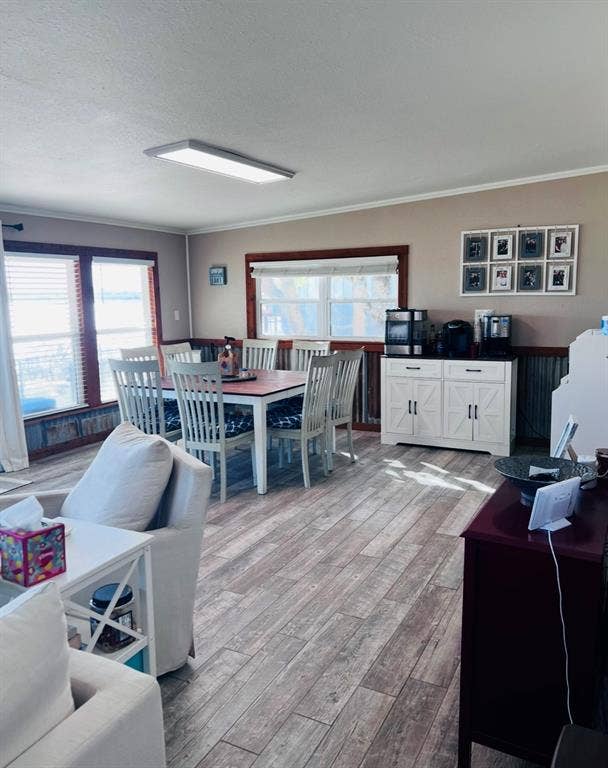 Wood-finish flooring throughout, multiple windows with blinds, and white decorative wainscoting