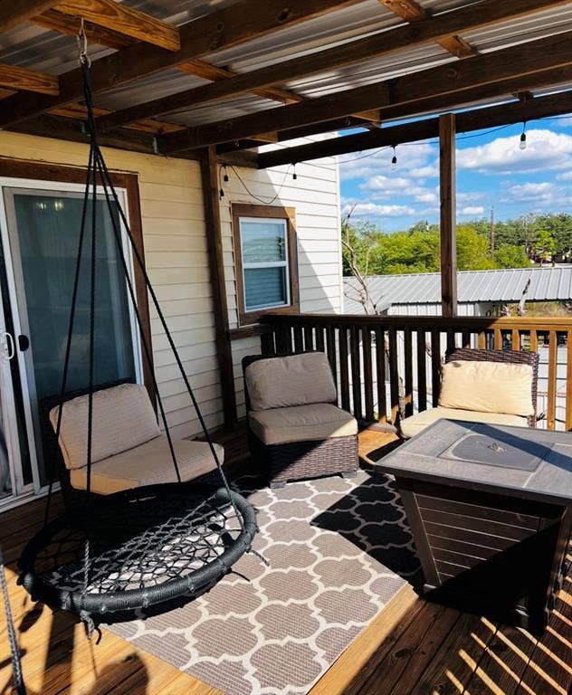 Covered wooden deck featuring a metal roof, wood beam supports, and wood siding