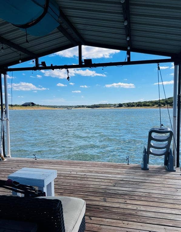 Covered dock with wood plank flooring and an expansive water backdrop