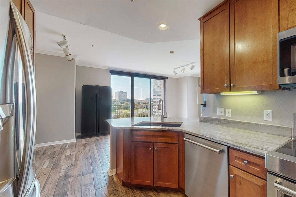 330 Las Colinas Boulevard E, #920, Irving, TX 75039 Kitchen featuring sink, light stone counters, appliances with stainless steel finishes, kitchen peninsula, and light hardwood / wood-style floors