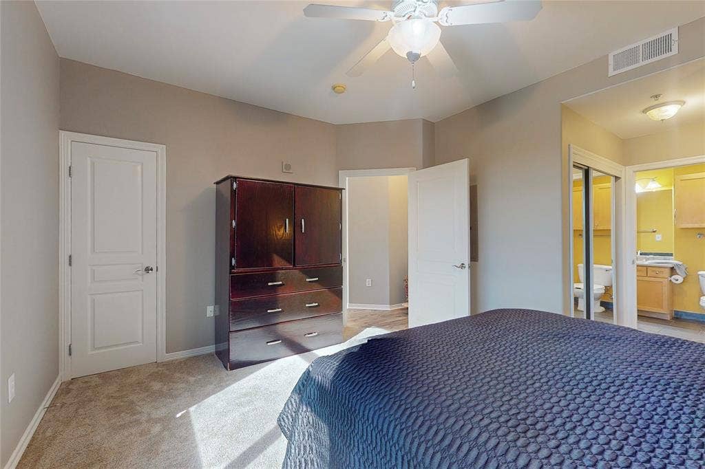 330 Las Colinas Boulevard E, #920, Irving, TX 75039 Bedroom with light carpet, connected bathroom, and ceiling fan