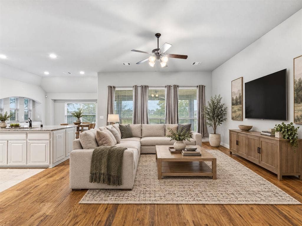 Open-concept room featuring wood-finish flooring, recessed lighting, a ceiling fan with integrated lighting, and a kitchen island with stone-finish countertops