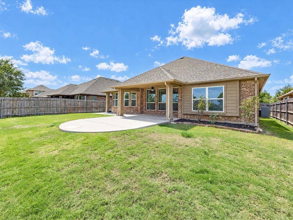 Brick and siding exterior featuring a covered patio, concrete slab, and wooden perimeter fencing
