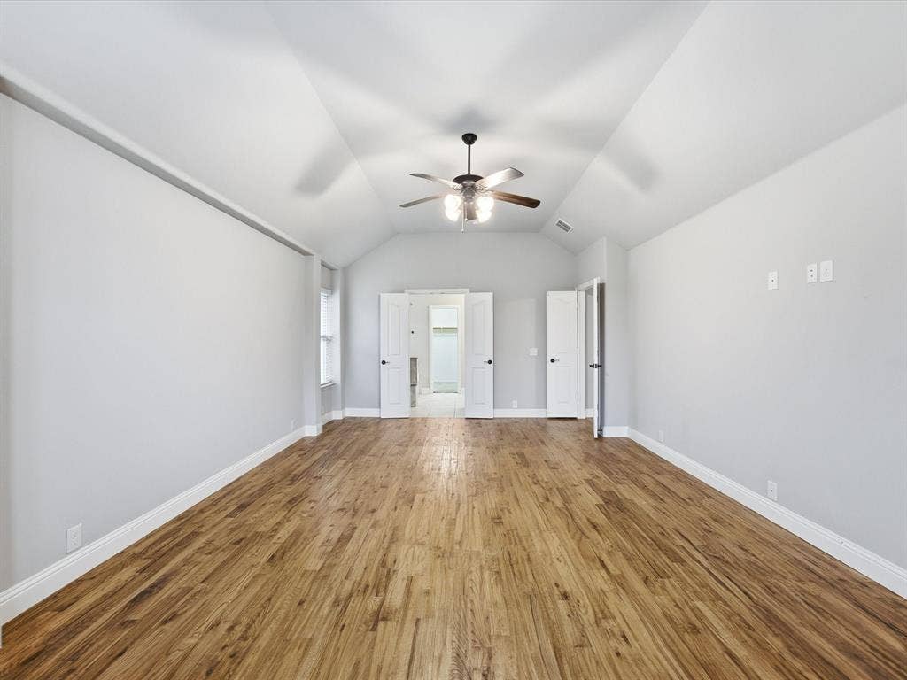 Vaulted ceilings, wood-finish flooring, numerous windows with integrated blinds, and a multi-blade ceiling fan with integrated lighting