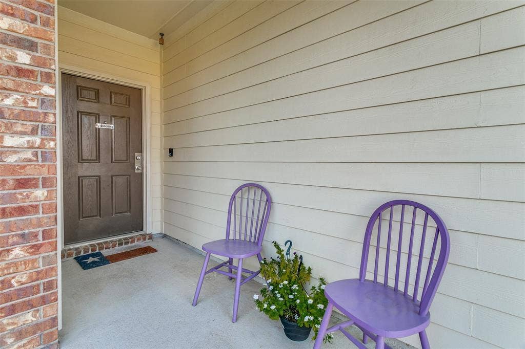 540 S Heights Drive, Crowley, TX 76036 Covered entryway featuring light-toned horizontal siding, a multi-panel door, and masonry exterior accent
