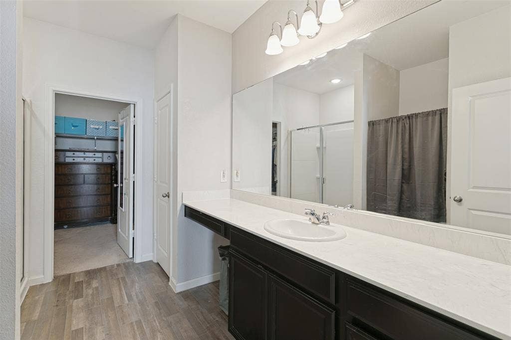 540 S Heights Drive, Crowley, TX 76036 Bathroom vanity featuring dark-toned cabinetry, a light-colored countertop, an oval undermount sink, a full-width mirror, and multi-bulb wall lighting